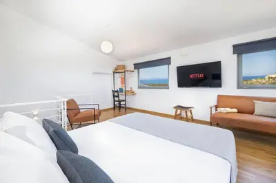 a bedroom with a bed and a couch and a tv at Sea Apt - Akrotiri in Kounoupidhianá