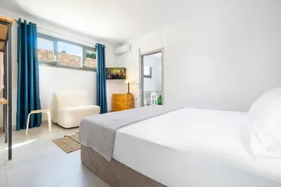 a white bedroom with a bed and a chair at Olive Apt - Akrotiri in Kounoupidhianá