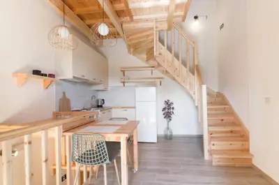a kitchen and dining room with a wooden table and stairs at House Of Ntounias ΙΙ in Dhrakóna
