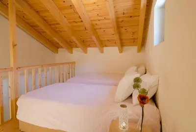a bedroom with a white bed with a wooden ceiling at House Of Ntounias ΙΙ in Dhrakóna