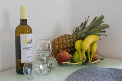 a bottle of wine next to a basket of fruit at Michael Apartments 2 in Agia Marina Nea Kydonias