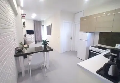 a white kitchen with a table and a counter at Vabis Koum - Kapi in Chania Town