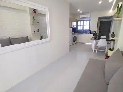 a white living room with a couch and a kitchen at Vabis Koum - Kapi in Chania Town