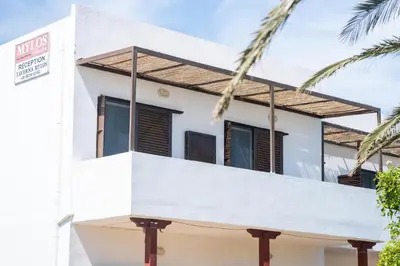 a white house with a balcony and palm trees at MYLOS (6) in Chania Town