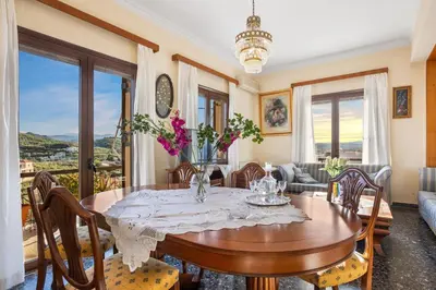 a dining room with a table with flowers on it at Sunset Apartment in Platanias in Plataniás