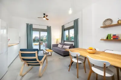 a kitchen and living room with a wooden table and chairs at Olisea Villa, olive grove seaview villa in Kounoupidhianá