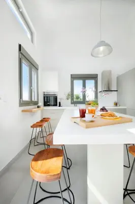 a kitchen with a white counter and some chairs at Olisea Villa, olive grove seaview villa in Kounoupidhianá