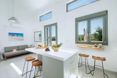 a kitchen with a white counter and stools at Olisea Villa, olive grove seaview villa in Kounoupidhianá