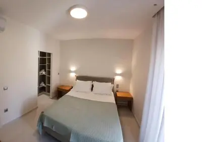 a bedroom with a bed and two tables and a window at White Dome Apartment I in Souda