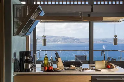 a kitchen with a counter with a view of the ocean at Eleni's Serenity - Discovering Sapphire Harmonies in Ravdhoúkha