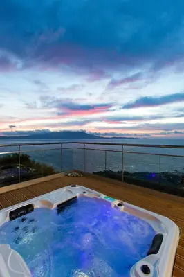 a bath tub on a balcony with a view of the ocean at Eleni's Serenity - Discovering Sapphire Harmonies in Ravdhoúkha