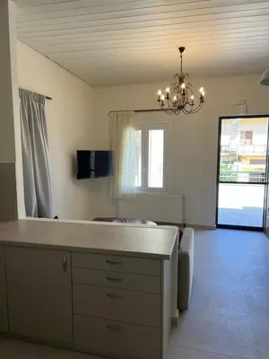 a living room with a table and a chandelier at The Gem Of Talos Apartment in Stalos