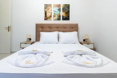 a bed with white blankets and pillows on it at Villa Giannari in Stalos