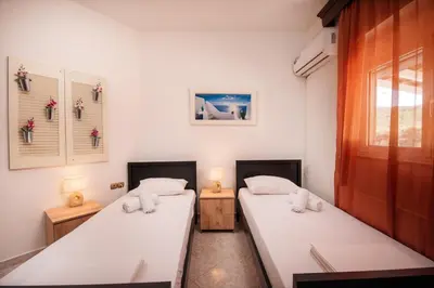 two beds in a room with two lamps and a window at Aptera Dream Apartment in Áptera