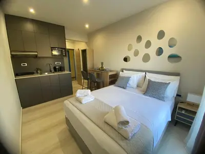 a bedroom with a large white bed and a kitchen at Rouan Studios in Souda