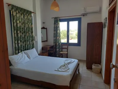 a bedroom with a bed and a window and a table at Lissos Studios - Rooms in Palaiochóra