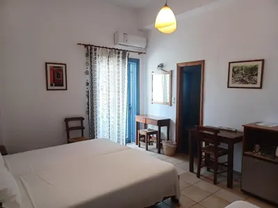 a bedroom with a bed and a desk and a window at Lissos Studios - Rooms in Palaiochóra