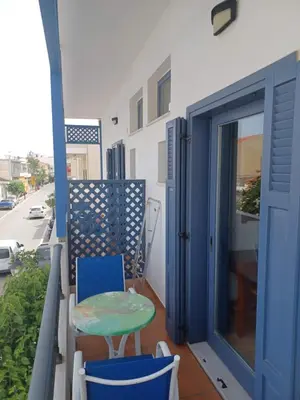a balcony with a blue door and a table and chairs at Lissos Studios - Rooms in Palaiochóra