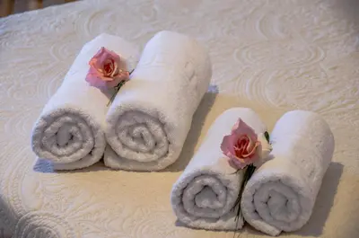 four rolls of towels with flowers on a table at Studios George in Palaiochóra