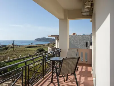 a balcony with two chairs and a table and the ocean at Kalami Apartments in Falasarna