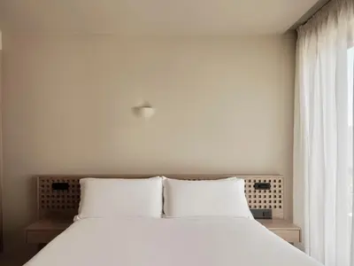 a white bed with white pillows and a window at Tella Thera, a Member of Design Hotels in Kissamos
