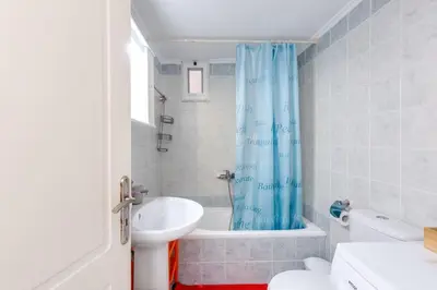 a bathroom with a blue shower curtain and a sink at Backyard Art Studio in Chania Town