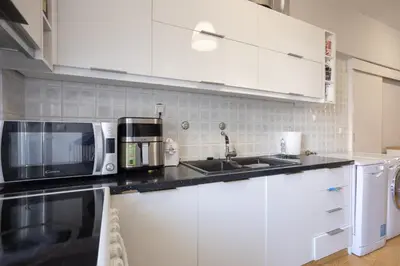 a kitchen with white cabinets and a microwave and a sink at Cozy Apartment 50m to beach, 5min walk to Old Town in Chania Town