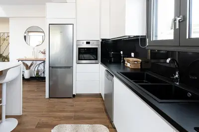 a kitchen with white cabinets and a stainless steel refrigerator at Galanidis Luxury Apartments in Perivólia