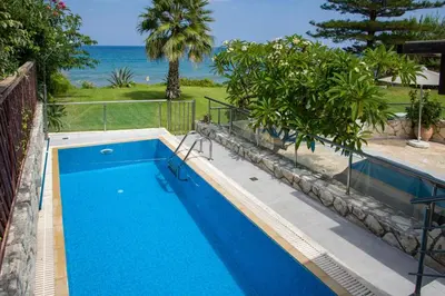 a blue swimming pool with the ocean in the background at The Seaside Villa in Chania Town