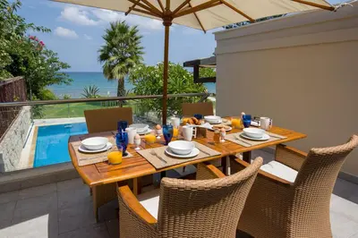 a wooden table with chairs and an umbrella next to a pool at The Seaside Villa in Chania Town