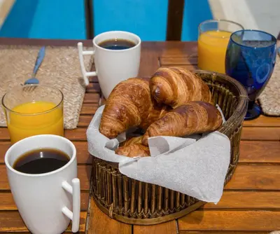 a basket of croissants and cups of coffee on a table at The Seaside Villa in Chania Town