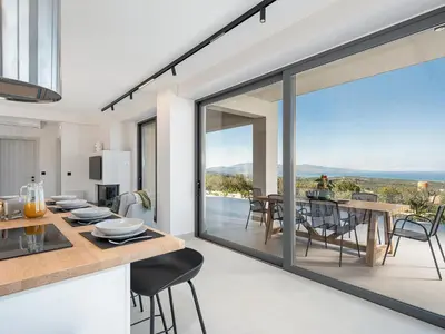 an open kitchen and dining room with a view of the ocean at Villa Levante With Sea View in Plataniás