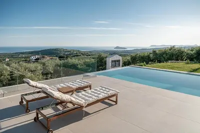 a pool with two lounge chairs next to a swimming pool at Villa Levante With Sea View in Plataniás