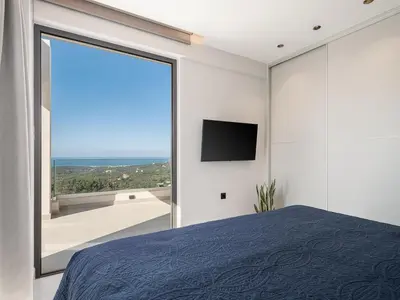 a bedroom with a large window and a tv at Villa Zefyros With Sea View in Plataniás