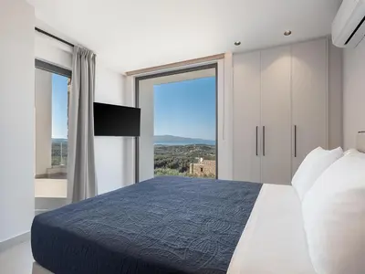 a bedroom with a large bed and a large window at Villa Zefyros With Sea View in Plataniás