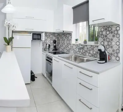a white kitchen with a sink and a stove at Modern House in the Old Town in Chania Town
