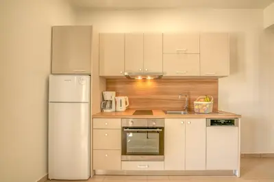 a kitchen with white cabinets and a white refrigerator at Koutris Apartment 1 in Falasarna