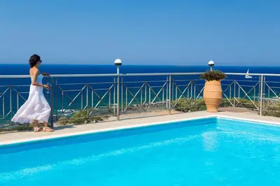 a woman in a white dress standing next to a swimming pool at Amazing sea views at villa Elafonissi with private pool, near Elafonissi beach in Chania Town