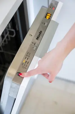 a woman is reaching for an oven handle at Seascape Kalyves in Kalyves