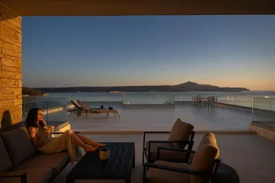 a woman sitting on a couch reading a book at Seascape Kalyves in Kalyves