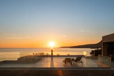 a sunset from the roof of a building with chairs and tables at Seascape Kalyves in Kalyves