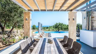 a patio with a table and chairs and a pool at Villa Annie Crete - Private Luxury Villa with Sea and Mountain Views in Tsivarás