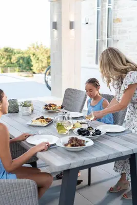 a woman and two children sitting at a table with food at Villa Annie Crete - Private Luxury Villa with Sea and Mountain Views in Tsivarás