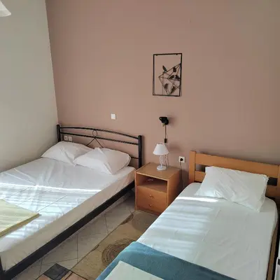 two twin beds in a room with a night stand at Rododafni Apartments in Kolymvari