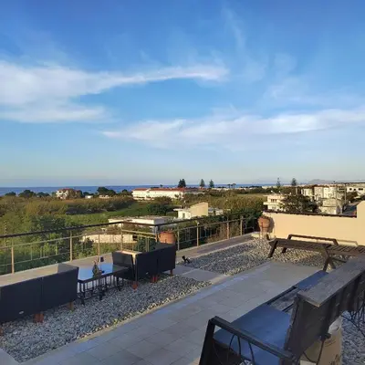 a patio with a bench and a view of the ocean at Rododafni Apartments in Kolymvari