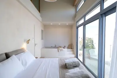 a bedroom with a white bed and a large window at Once Upon a Home in Chania Town
