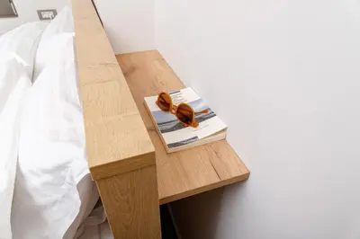 a book on a wooden shelf next to a bed at Penny's Apartment in Chania Town