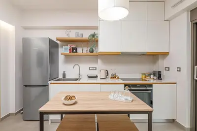a kitchen with white cabinets and a wooden table at Penny's Apartment in Chania Town