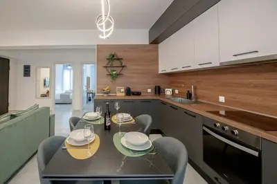 a kitchen with a table and chairs and a kitchen with white cabinets at Luxury Chic Retreat Suites in Chania Town