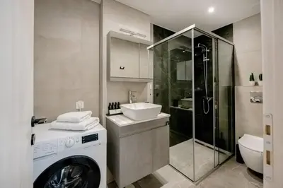 a bathroom with a washing machine and a sink at Boho Chic Retreat Suite in Chania Town